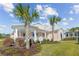 Charming single-story home has an inviting porch, with lush landscaping featuring palm trees and green lawn at 1042 Sugarloaf Key Loop, Lady Lake, FL 32159