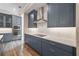 A modern kitchen with white countertops and backsplash, blue cabinets, and stainless steel appliances, plus wood-look floors at 1042 Sugarloaf Key Loop, Lady Lake, FL 32159