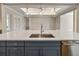 A sink with stainless steel faucet on a kitchen island with quartz countertops and blue cabinets, plus pendant lighting at 1042 Sugarloaf Key Loop, Lady Lake, FL 32159