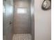 Modern bathroom shower offers stylish gray tile, mosaic floor, and sleek fixtures at 1057 Sugarloaf Key Loop, Lady Lake, FL 32159