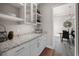Elegant butler's pantry with granite countertops, white cabinets, and view of dining room at 1057 Sugarloaf Key Loop, Lady Lake, FL 32159