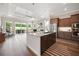 Open concept kitchen with island, stainless appliances, wood floors and a connecting living space at 1057 Sugarloaf Key Loop, Lady Lake, FL 32159