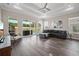 Open living room with hardwood floors, tray ceilings, and large windows offering serene outdoor views at 1057 Sugarloaf Key Loop, Lady Lake, FL 32159