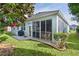 Charming backyard with a lush green lawn, screened in patio, and mature trees at 1122 Magrath Way, The Villages, FL 32162