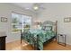 Comfortable bedroom with a tropical-themed bedspread and lots of natural light at 1122 Magrath Way, The Villages, FL 32162