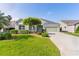 Home featuring a well-manicured lawn, beautiful landscaping and long driveway at 1122 Magrath Way, The Villages, FL 32162