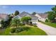 Single-story home with a well-manicured lawn, beautiful landscaping and long driveway at 1122 Magrath Way, The Villages, FL 32162