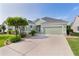 Home featuring a well-manicured lawn, beautiful landscaping and long driveway at 1122 Magrath Way, The Villages, FL 32162