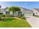 Charming single-story home featuring a well-manicured lawn, mature landscaping, and a two-car garage at 1122 Magrath Way, The Villages, FL 32162