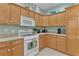 Traditional kitchen featuring wooden cabinets, granite counters, and a white gas range at 1122 Magrath Way, The Villages, FL 32162