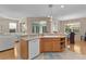 Open kitchen with a view of the living and dining areas, featuring wood cabinets and stainless steel dishwasher at 1122 Magrath Way, The Villages, FL 32162
