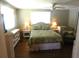 Comfortable bedroom with wood floors, ceiling fan, and a large window at 114 Azalea Trl, Leesburg, FL 34748