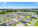 Wide aerial shot of a community with houses, green lawns, and serene ponds under a partly cloudy sky at 1225 Eunice St, The Villages, FL 34762