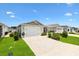 Charming home exterior with a well-kept lawn, spacious driveway, and attached garage under a sunny sky at 1225 Eunice St, The Villages, FL 34762