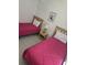 Comfortable bedroom featuring two twin beds with pink bedding, a nightstand, and neutral wall decor at 130 Napoli Dr, Davenport, FL 33897