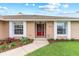 Charming home featuring a red front door, large windows, manicured lawn and landscaping at 1414 Cove Pl, Tavares, FL 32778