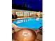 A luxurious pool area at night features relaxing lounge area with a modern firepit, perfect for entertaining guests at 1414 Cove Pl, Tavares, FL 32778