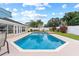 Sparkling pool with a sun-drenched patio, surrounded by lush landscaping and privacy fencing at 1414 Cove Pl, Tavares, FL 32778