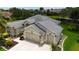 Angled shot of the home's exterior featuring a three car garage, landscaping, and flag at 1553 Lynchburg Loop, The Villages, FL 32162