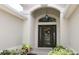 Elegant front entrance with a decorative wreath, transom window, and lush landscaping at 1553 Lynchburg Loop, The Villages, FL 32162