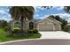 Lovely single-story home featuring a three-car garage, manicured lawn, and beautiful landscaping under a sunny sky at 1553 Lynchburg Loop, The Villages, FL 32162