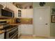 Well-lit kitchen with stainless steel appliances, granite countertops, white cabinets and decorative details at 1553 Lynchburg Loop, The Villages, FL 32162