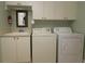Well-equipped laundry room with washer, dryer, utility sink, ample storage cabinets and neutral color scheme at 1553 Lynchburg Loop, The Villages, FL 32162