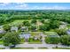 Aerial view of homes with green lawns, mature trees and a glimpse of a lake in the distance at 15916 Indian Wells Ct, Clermont, FL 34711
