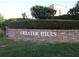 Entrance to the Greater Hills community with manicured hedges and brick sign; enjoy the beautiful landscaping at 15916 Indian Wells Ct, Clermont, FL 34711
