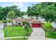 Inviting single-Gathering home with mature trees, well-maintained lawn, and a red garage door at 15916 Indian Wells Ct, Clermont, FL 34711