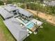 Aerial view of a modern luxury home featuring a pool, spa, and impeccably manicured landscaping in a secluded setting at 16320 Pendio Dr, Bella Collina, FL 34756