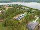 Aerial view of sprawling lakeside estate with meticulously landscaped grounds surrounded by lush trees at 16320 Pendio Dr, Bella Collina, FL 34756
