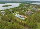 Aerial view of a luxury home with a lush green backyard, nestled amongst dense trees and near a serene lake at 16320 Pendio Dr, Bella Collina, FL 34756