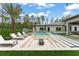 A modern backyard patio features a sunken lounge, an in-ground pool, and meticulous landscaping at 16320 Pendio Dr, Bella Collina, FL 34756