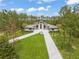 Expansive home exterior with a long driveway, symmetrical landscaping, and a striking modern design nestled amongst tall trees at 16320 Pendio Dr, Bella Collina, FL 34756
