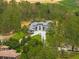 Aerial view of a modern home with a grand entrance, long driveway, and lush green landscaping surrounded by mature trees at 16320 Pendio Dr, Bella Collina, FL 34756