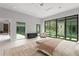 Modern main bedroom with neutral colors, large windows with backyard pool views and bench at 16320 Pendio Dr, Bella Collina, FL 34756