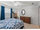 Bright bedroom with wood dresser, oval mirror, door, and a comfy bed with a patterned blue quilt at 17461 Se 82Nd Albemarle Ave, The Villages, FL 32162