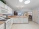 Open-concept kitchen showcasing white cabinets, neutral countertops, and views into the living space at 17461 Se 82Nd Albemarle Ave, The Villages, FL 32162