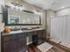 Bathroom featuring a double sink vanity, large mirror, walk-in shower, and wood-look flooring at 1824 Forest Glen Dr, Fruitland Park, FL 34731