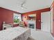 Comfortable bedroom featuring a fireplace, large window overlooking greenery, red walls and neutral carpeting at 1824 Forest Glen Dr, Fruitland Park, FL 34731