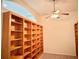 Bright home office featuring expansive built-in wooden bookshelves and a ceiling fan at 20936 Royal St Georges Ln, Leesburg, FL 34748