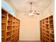 Bright home office featuring expansive built-in wooden bookshelves and a ceiling fan at 20936 Royal St Georges Ln, Leesburg, FL 34748