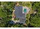 Aerial view of a meticulously maintained home with dark roof and inviting pool surrounded by lush landscaping at 2214 Dogwood Cir, Mount Dora, FL 32757