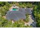Aerial view of a meticulously maintained home with dark roof, lush landscaping, inviting pool area, and circular driveway at 2214 Dogwood Cir, Mount Dora, FL 32757