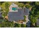 An aerial view of the property with a home with a dark roof, a pool and patio area, and mature trees at 2214 Dogwood Cir, Mount Dora, FL 32757
