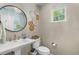 Stylish powder room features a round mirror, elegant light fixture, and a bright window at 2214 Dogwood Cir, Mount Dora, FL 32757