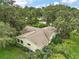 Aerial view of the yellow siding house with a shingle roof surrounded by mature trees and lush landscaping at 24 Brigadoon Cir, Leesburg, FL 34788