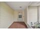 Covered entryway with brick flooring leading to the front door, next to sidelight window at 24 Brigadoon Cir, Leesburg, FL 34788