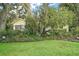 Landscaped front yard filled with mature shrubbery and trees surrounding the house with lush green grass at 24 Brigadoon Cir, Leesburg, FL 34788
